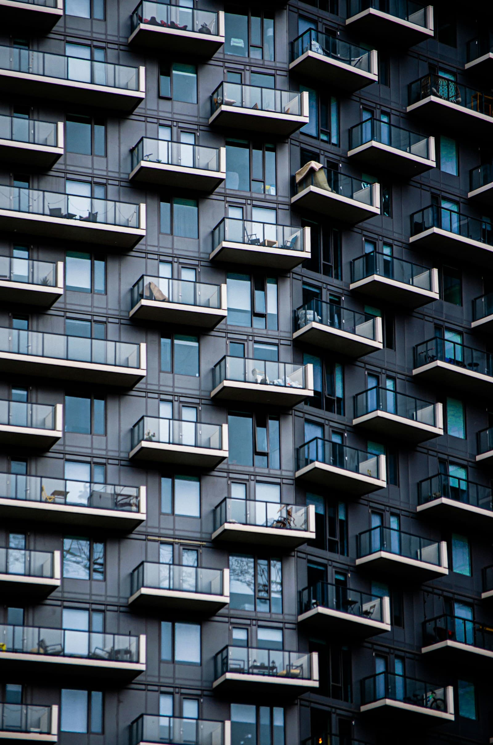 Dark modern apartment facade with rows of glass balconies
